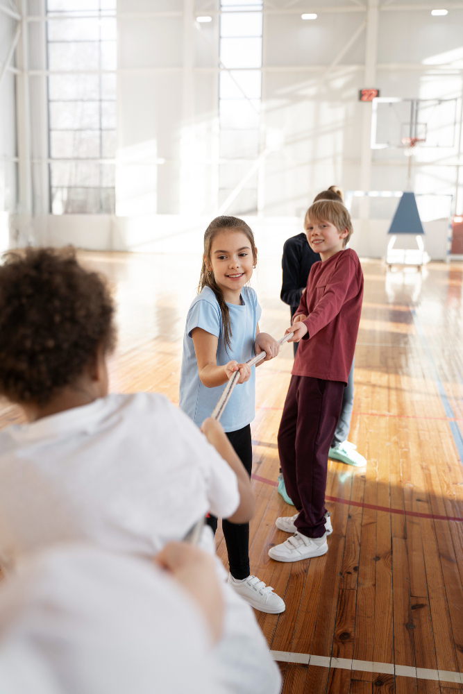 Kinder spielen Tauziehen in einer Turnhalle mit Holzboden