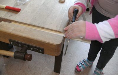 Kind bei Holzarbeit in Werkstatt mit Säge aktive Lernumgebung