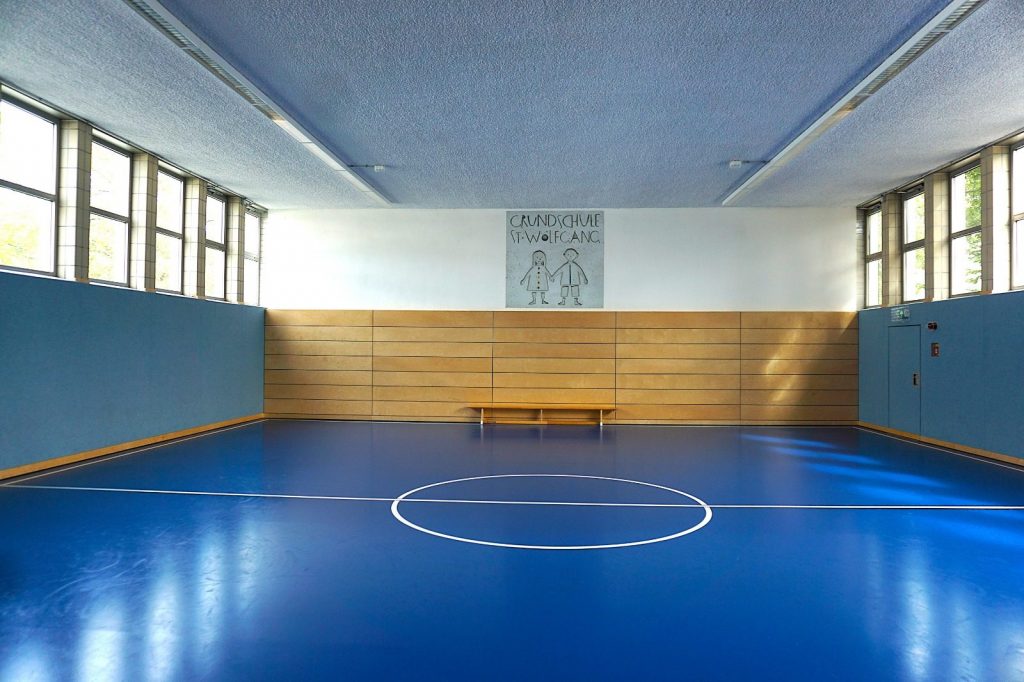 Leere Sporthalle mit blauem Boden und Holzverkleidung