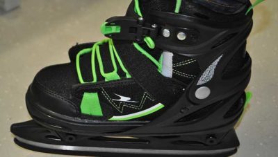 Schwarzer Schlittschuh mit grünem Akzent auf grauem Boden