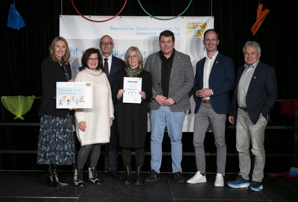 Menschen bei einer Preisverleihung vor einem dekorativen Banner