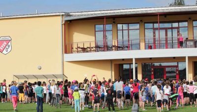 Versammlung von Menschen vor einem modernen Sportgebäude