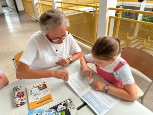 Ältere Frau hilft jungem Mädchen beim Lernen in der Bibliothek