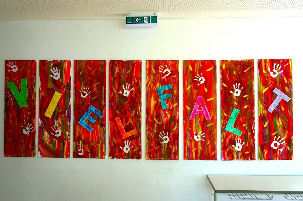 Buntes Wandgemälde mit dem Wort Vielfalt und Handabdrücken