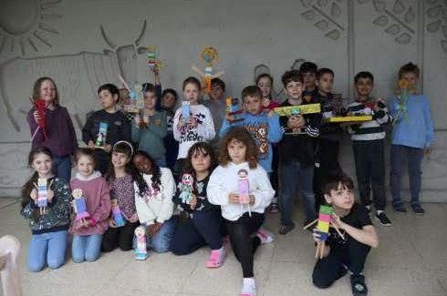 Eine Gruppe von Kindern präsentiert bunte Bastelarbeiten.